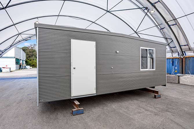 Finished light gauge modular building with corrugated cladding, door and window, inside a fabric shelter